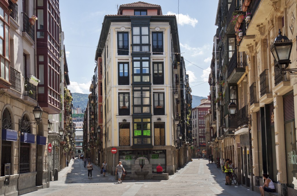 Bilbao, Spain - July 29, 2013: the old centre of Bilbao (barrio viejo), a pedestrian shopping zone with only a few people walking the sunlit streets because of siesta at midday when shops are closed.